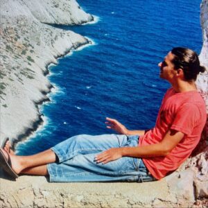 Christoffer Hiding sitter på en mur och blickar ut över havet.