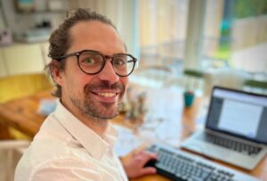 Christoffer Hiding i vit skjorta framför datorn.